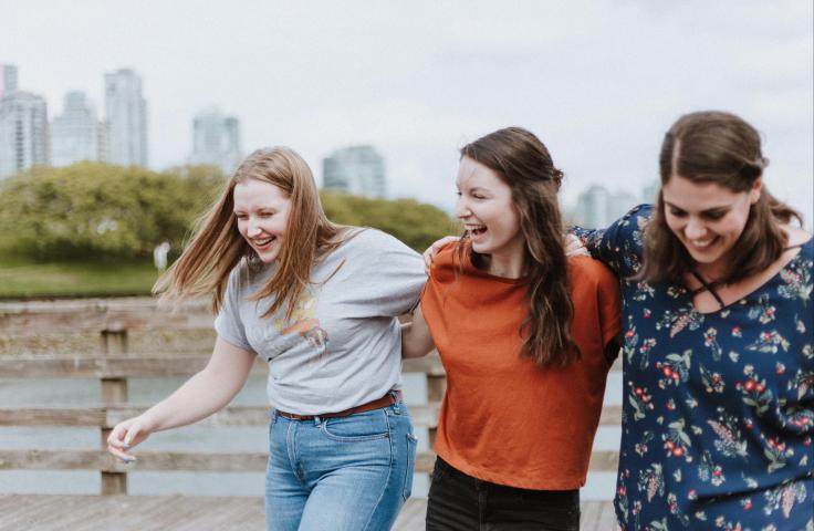 Trois femmes riant, bras dessus, bras dessous