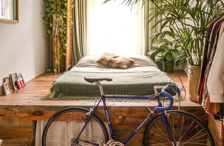 Chambre bohème avec lit, parquet, plantes et vélo