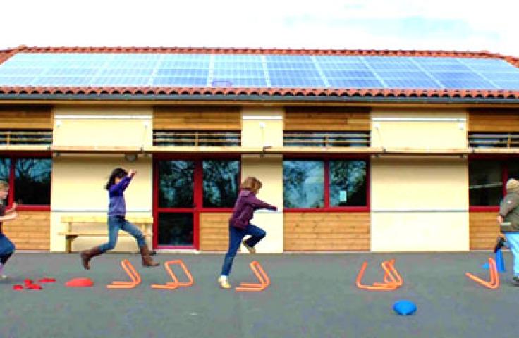 Enfants jouant devant un bâtiment avec panneaux solaires