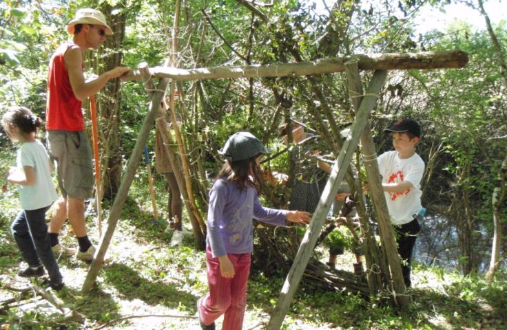 Adulte et enfants construisant un abri en bois