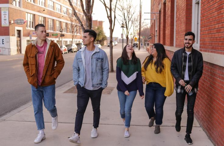 5 jeunes marchant sur un trottoir 