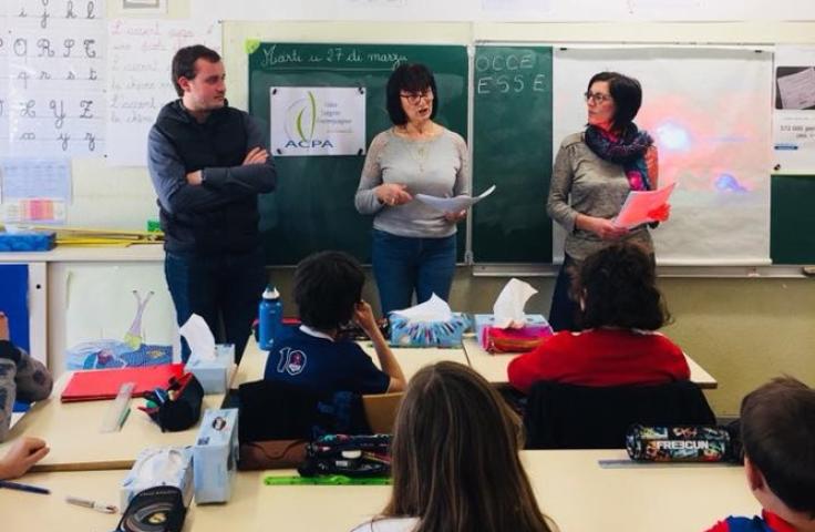 Trois professeurs (deux femmes, un homme) debout devant le tableau noir, dans une salle de classe