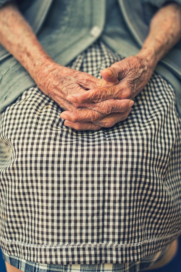 Mains d'une personne âgées posées sur ses jambes