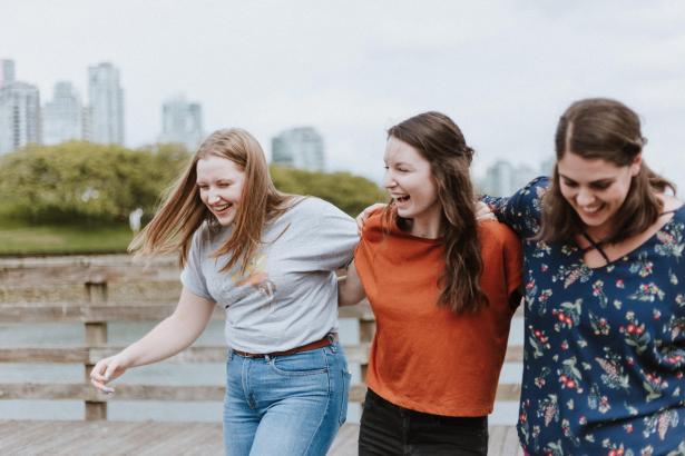 Trois femmes riant, bras dessus, bras dessous