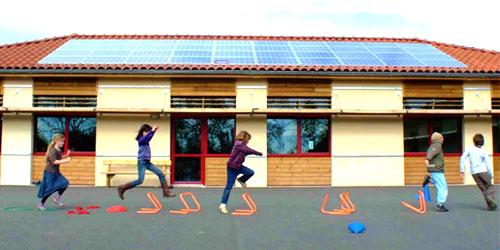 Enfants jouant devant un bâtiment avec panneaux solaires