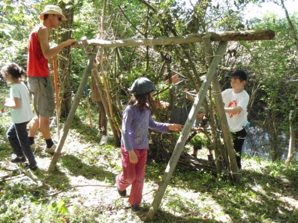 Adulte et enfants construisant un abri en bois